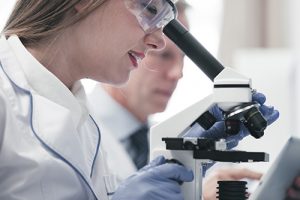 Clinical Research Student looking into Microscope