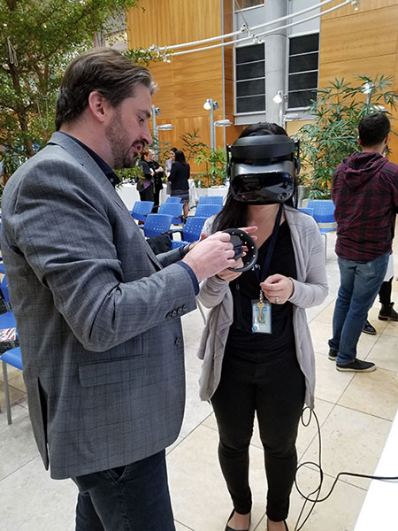 Jordan Holmes shows an individual how to use the virtual reality equipment