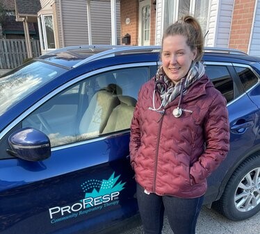 Michener alumna Chelsea Mott standing in front of a car