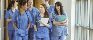 Five medical students walking down a hall and talking