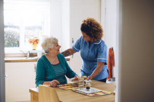 Care worker giving an old lady her dinner in her home.assisting elderly woman