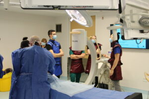 C-arm X-ray machine positioned over a table while surgical residents and Michener students watch