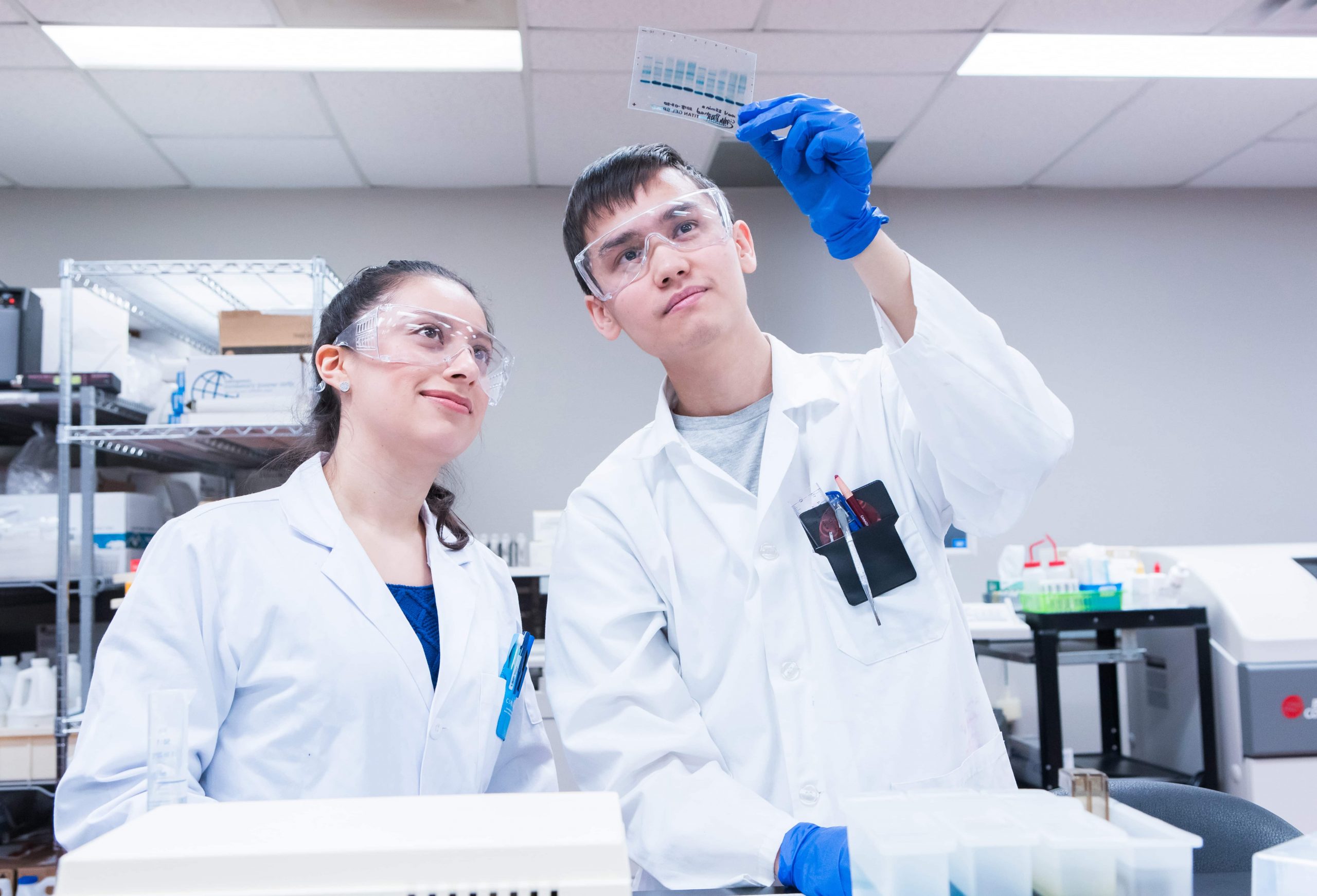 Two medical students hold up and analyze a medical sample.