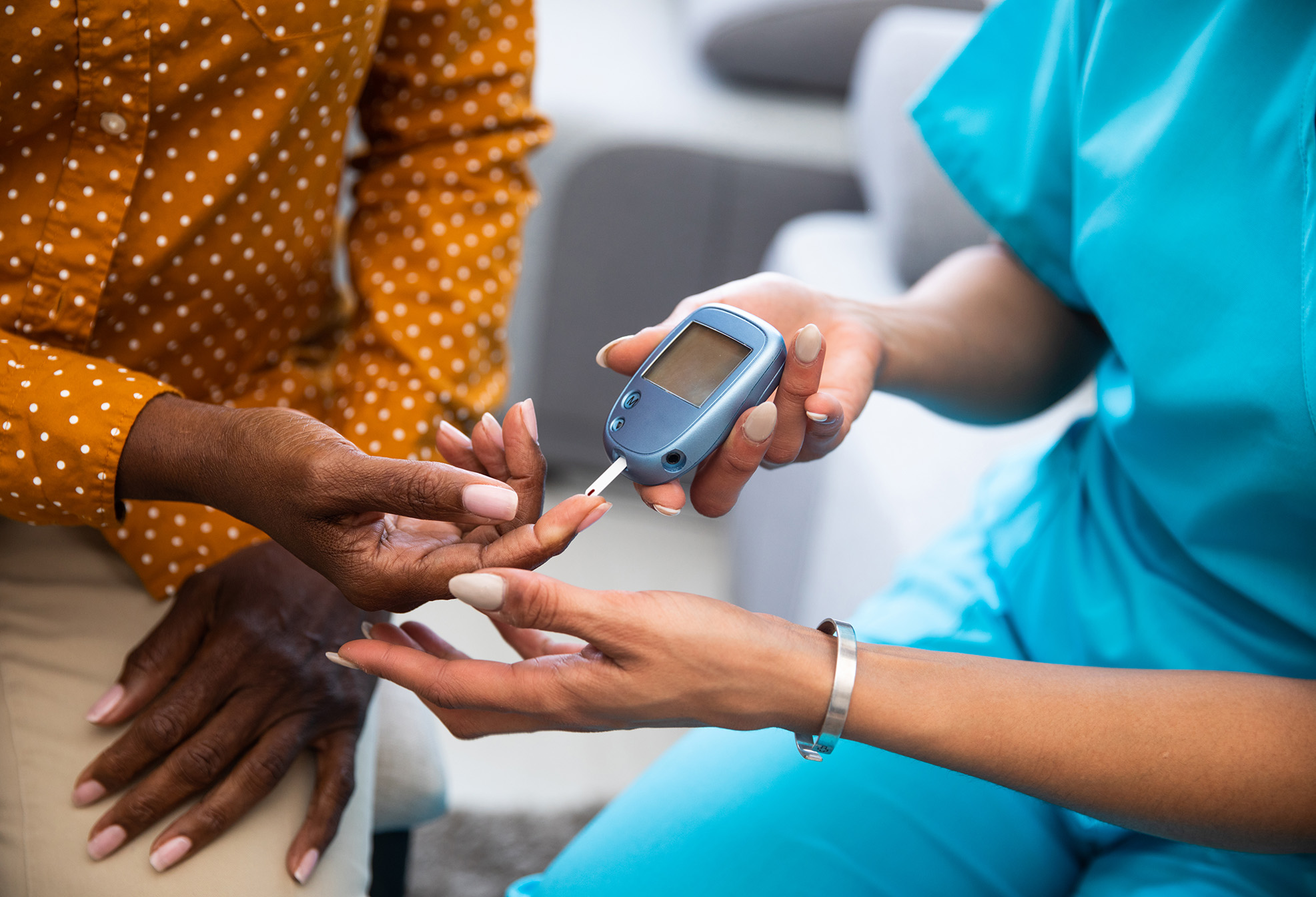 A healthcare worker checks a patient's blood sugar level using a glucose meter and test strip.