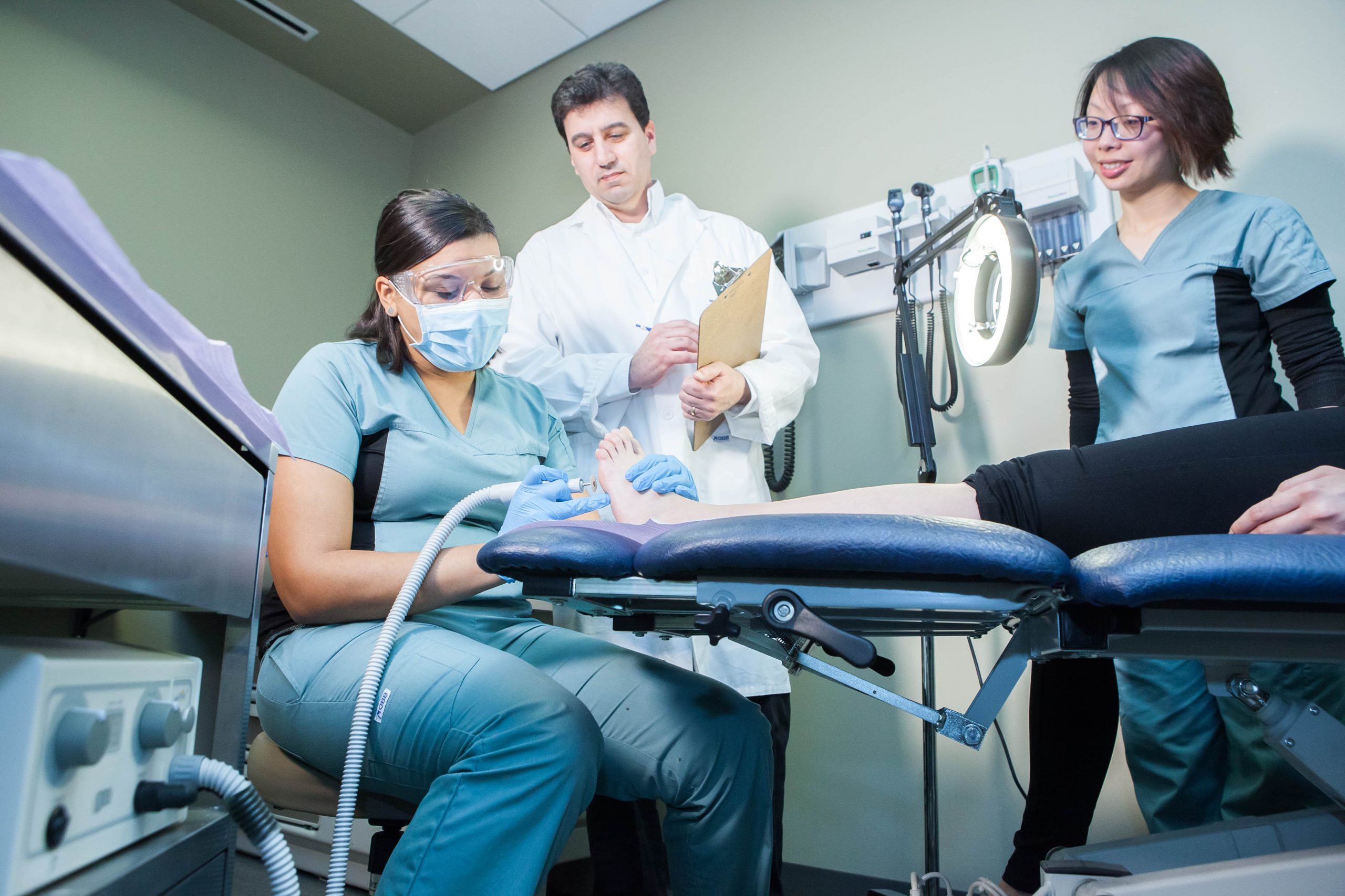 A medical team conducts a foot examination on a patient in a clinical setting.