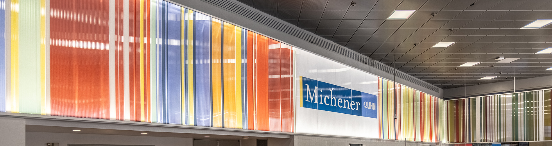 Wide view of a building interior with colourful vertical stripes and a sign reading "Michener" on the wall.