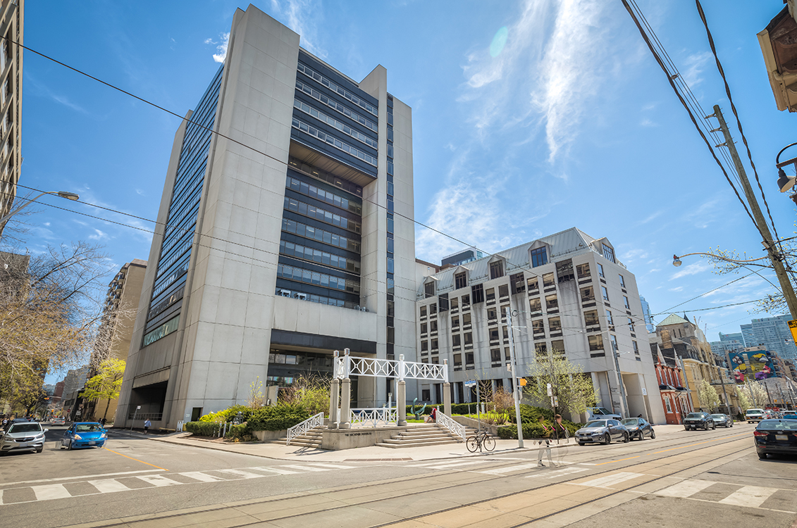 Tall modern concrete buildings on a city street under a clear blue sky.