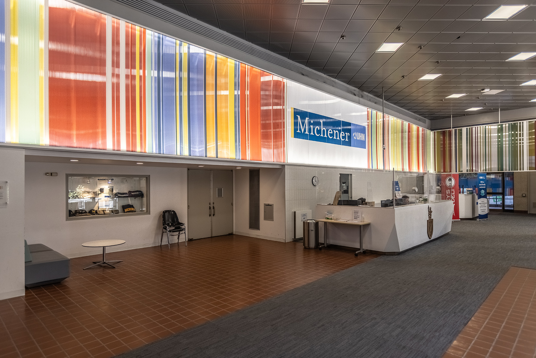 Lobby area with colourful striped wall panels, a reception desk with "Michener" sign.