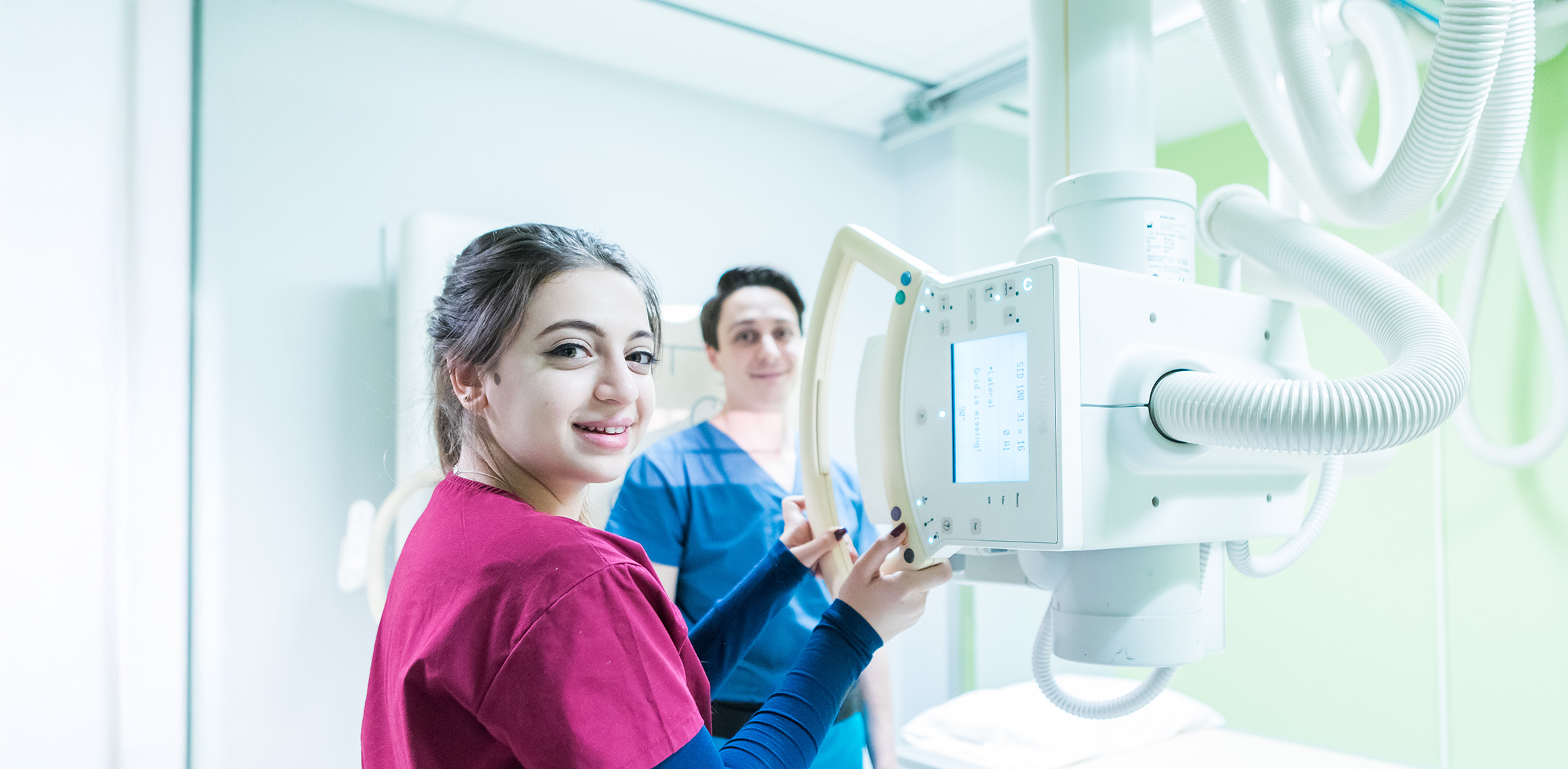Radiological technology students operating an X-ray machine in a clinical training lab.